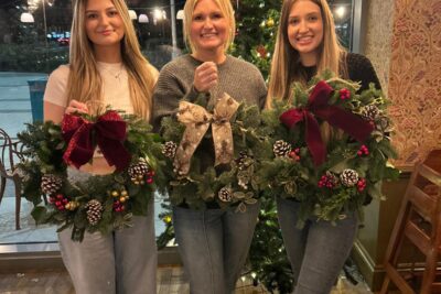 Three people in Vallado Lounge holding wreaths they made