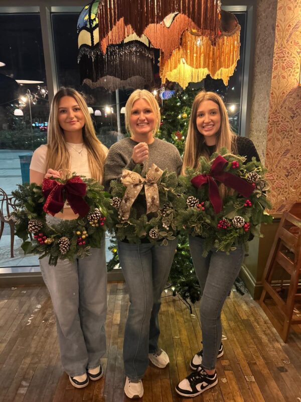 Three people in Vallado Lounge holding wreaths they made